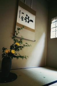 un vaso con fiori gialli in una stanza con un cartello di Ryokan Tori a Kyoto