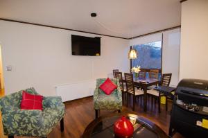 a living room with a table and chairs and a television at Departamento Andes Chillan in Nevados de Chillan