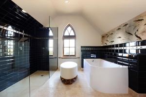 a bathroom with a white tub and black tiles at The Church House Gourmet Retreat in Fish Creek