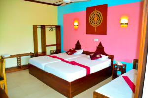 twee bedden in een kamer met roze en kleurrijke muren bij The Triangle Hotel in Anuradhapura