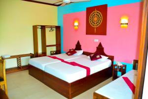 two beds in a room with pink and colorful walls at The Triangle Hotel in Anuradhapura