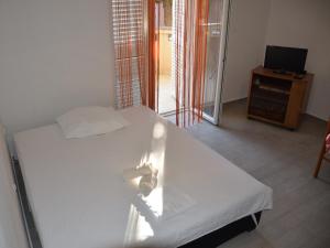 a bedroom with a white bed and a television at Apartment Summer Paradise in Novalja