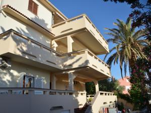 a white house with a balcony with palm trees at Apartment Summer Paradise in Novalja