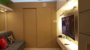 een woonkamer met een tv en een bank en een klok bij Tagaytay Condotel in Tagaytay