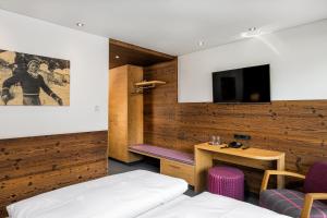 a room with a bed and a desk and a tv at Hotel Garni Ernst Falch in Sankt Anton am Arlberg