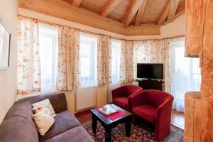 uma sala de estar com um sofá e duas cadeiras e uma televisão em Alimonte Romantic Appartements em Sankt Johann in Tirol