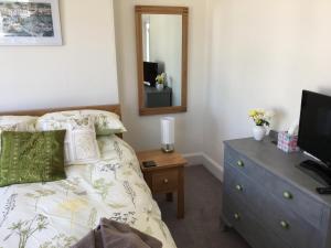 a bedroom with a bed and a dresser with a mirror at Penwyn Bed and Breakfast in Looe