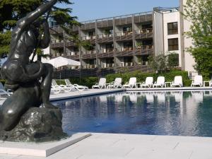 Eine Statue einer Frau auf einem Felsen neben einem Schwimmbad. in der Unterkunft Hotel Acquaviva Del Garda in Desenzano del Garda