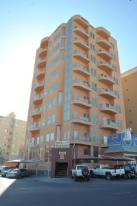 a tall building with cars parked in front of it at Terrace Furnished Apartments Fintas 2 in Kuwait