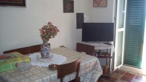 una stanza con tavolo, televisore e vaso di fiori di Un viaggio nel tempo a Tortoreto