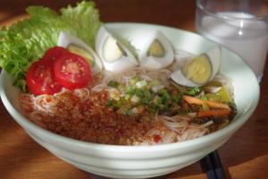 a bowl of noodles with eggs and vegetables on a table at Lijiang Merry Inn in Lijiang +42 photos