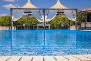 una piscina con sedie e un gazebo di Valle Degli Dei AgriResort a Noto