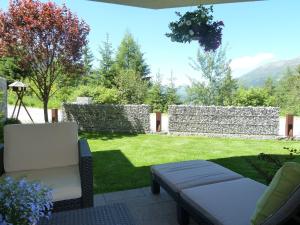 a backyard with a stone wall and a chair and a lawn at Ferienwohnung Gritsch in Jerzens