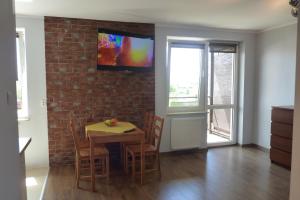 una sala da pranzo con tavolo e TV su un muro di mattoni di Apartament Młyńska a Zamość