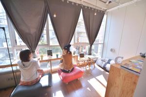 Chillulu Hostel في يوكوهاما: بنتان جالستان على طاولة في غرفة بها نوافذ
