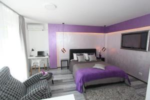 Dormitorio púrpura con cama y silla en New Belgrade Apartment ARENA en Belgrado