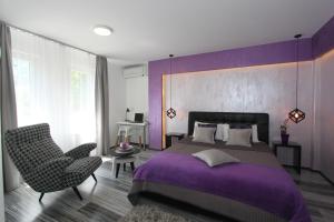 Dormitorio púrpura con cama y silla en New Belgrade Apartment ARENA en Belgrado