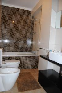 a bathroom with a toilet and a sink and a tub at Diamante Azul Barra Beach Apartment in Praia da Barra