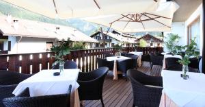 ein Restaurant mit Tischen und Sonnenschirmen auf einer Terrasse in der Unterkunft Royal Olympic Hotel in Pinzolo