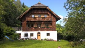 une grande maison en bois avec un toit en gambrel dans l'établissement Rauter in Wöllan, à Arriach
