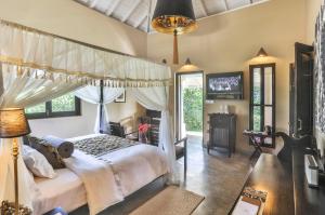 a bedroom with a canopy bed and a television at Villa Mayurana by Edwards Collection in Koggala