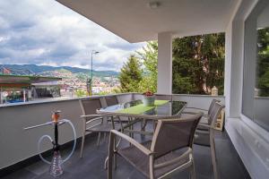 einen Tisch und Stühle auf einem Balkon mit Aussicht in der Unterkunft Green Elite Residence in Sarajevo