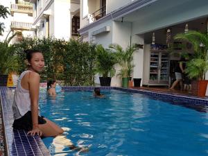a girl is standing in a swimming pool at Smiley's Guesthouse in Siem Reap