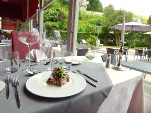 - une table avec une assiette de nourriture et des verres à vin dans l'établissement Le Grand Hotel de Plombières by Popinns, à Plombières-les-Bains