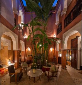 un vestíbulo con una gran planta, mesas y sillas en Dar Attajmil, en Marrakech