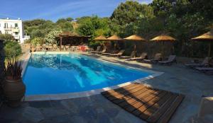 a pool with chairs and umbrellas at a hotel at Vassiliki Studios in Andros