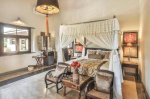 a bedroom with a canopy bed with chairs and a table at Villa Mayurana by Edwards Collection in Koggala