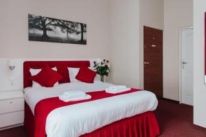 a bedroom with a large bed with red and white sheets at Rembrandt Aparthotel in Kraków