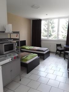 a room with two beds and a kitchen with windows at Pension zum Bauhof in Zwickau