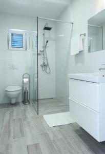 uma casa de banho branca com um chuveiro e um WC. em Apartments Mocici em Cilipi