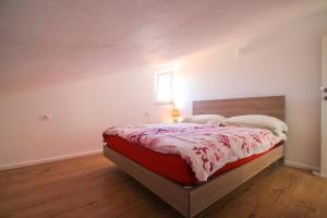 a bedroom with a bed with a red and white comforter at Apartments Jadranka Sain in Novigrad Istria