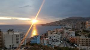 uma cidade com o pôr do sol sobre a água em Apartments Saranda em Sarandë