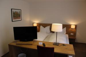 a hotel room with a desk with a television and a bed at Gasthof und Pension zum Löwen in Hirschberg an der Bergstraße