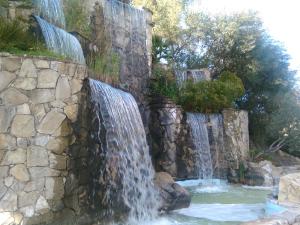 a waterfall in a garden with a stone wall at Hotel Casa Paco in El Bosque