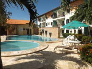 a swimming pool with a table and an umbrella and a building at CONDOMÍNIO VILA DO MAR aptos 201C e 211B in Aquiraz