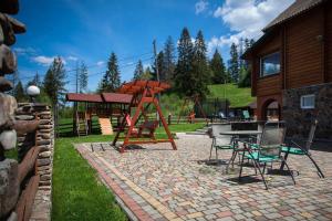 a playground with a swing and a table and chairs at Lisoviy Zatyshok in Slavske