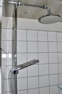 a shower in a bathroom with white tiles at Artistiek Vakantiehuisje in Hulst