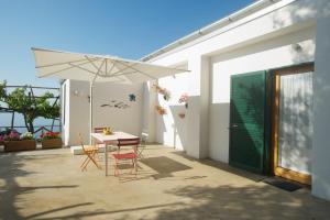 a patio with a table and a white umbrella at Sopra il Limoneto in Cetara