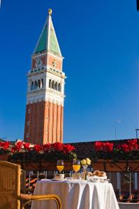 una torre dell'orologio con un tavolo di fronte a un edificio di Albergo San Marco a Venezia