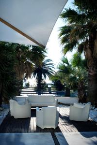 a patio with white chairs and palm trees at Hotel Roma in Grottammare