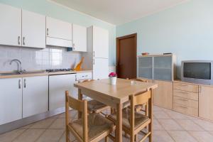 a kitchen with white cabinets and a wooden table and chairs at Sul Mare Smith in Lido degli Estensi