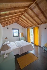 a bedroom with a white bed and yellow curtains at Casa do André (Casas do Capelo) in Fajã