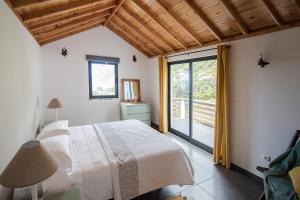 a bedroom with a bed and a large window at Casa do André (Casas do Capelo) in Fajã
