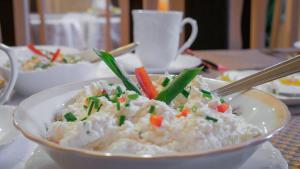 a bowl of rice with carrots and green onions at Noclegi Sebastian w Centrum in Ustrzyki Dolne