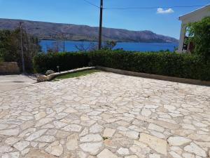 a large stone patio with a view of the water at Apartmani Jokić - family only in Pag