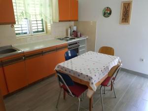 a kitchen with a table and chairs and a kitchen with orange cabinets at Apartmani Jokić - family only in Pag